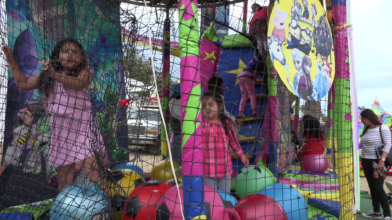 A girl stands near the center of the netted trampoline area in San Jose del Cabo, Mexico, while another child is close to the mesh and bright padded play forms fill the foreground.