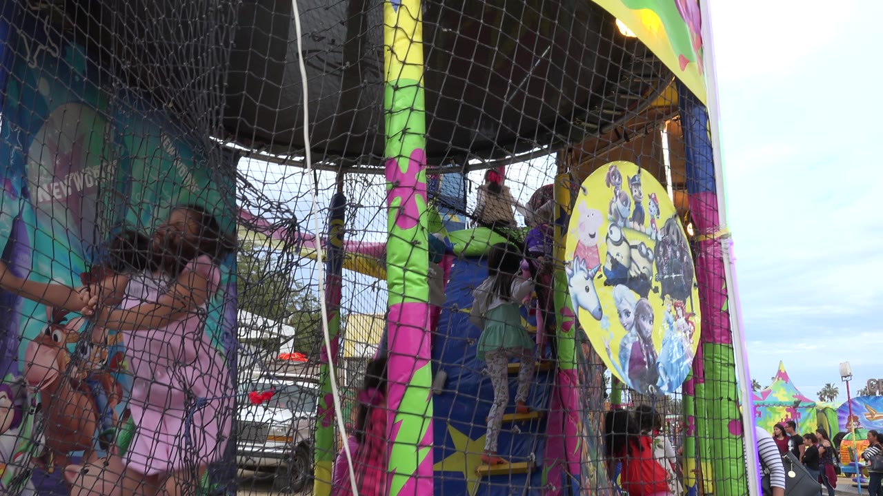Children inside a netted colorful play ride with ball seats.
