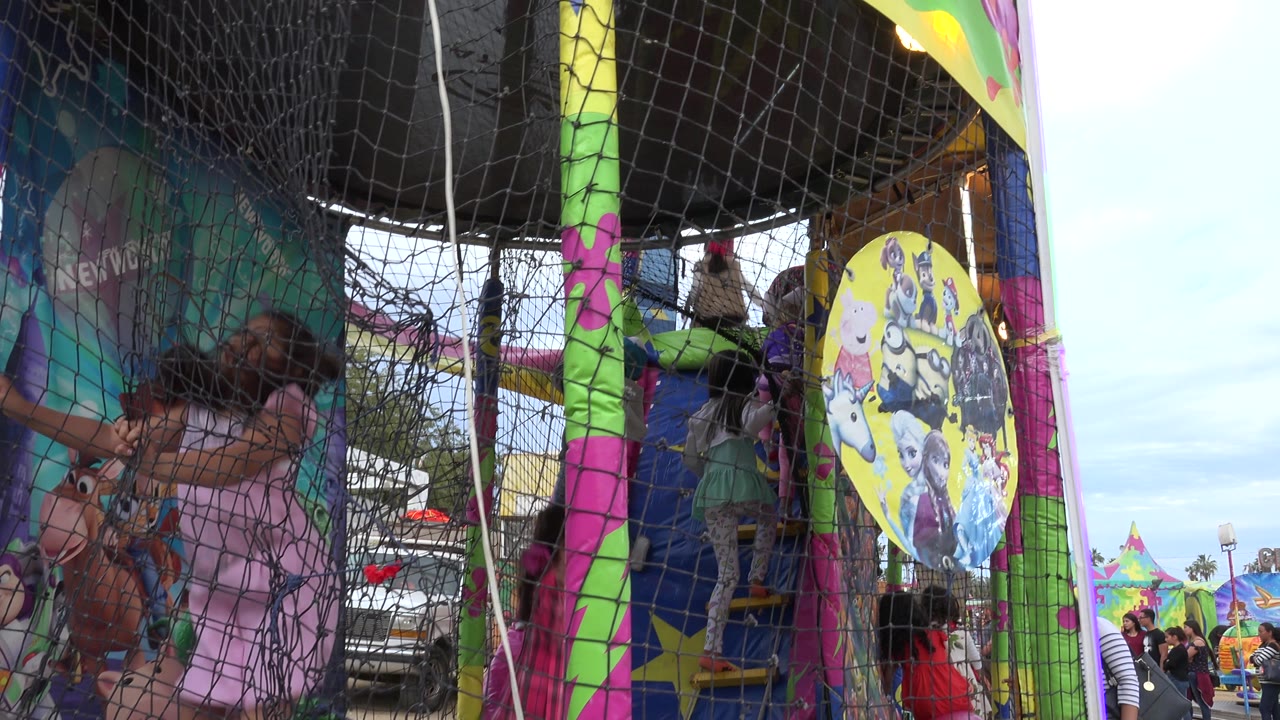 A child in pink stands close to the netting inside the San Jose del Cabo amusement ride while other children remain deeper in the structure near the stairs.