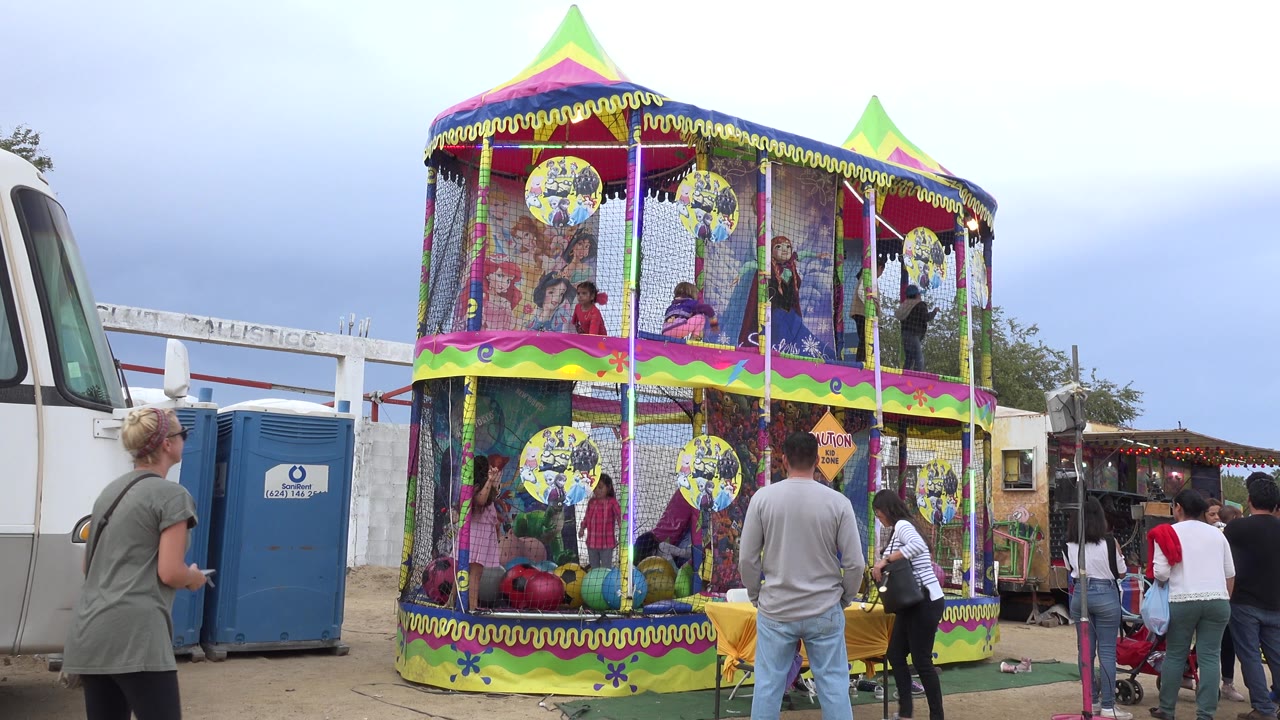 Colorful two-level amusement play structure with children inside and adults watching.