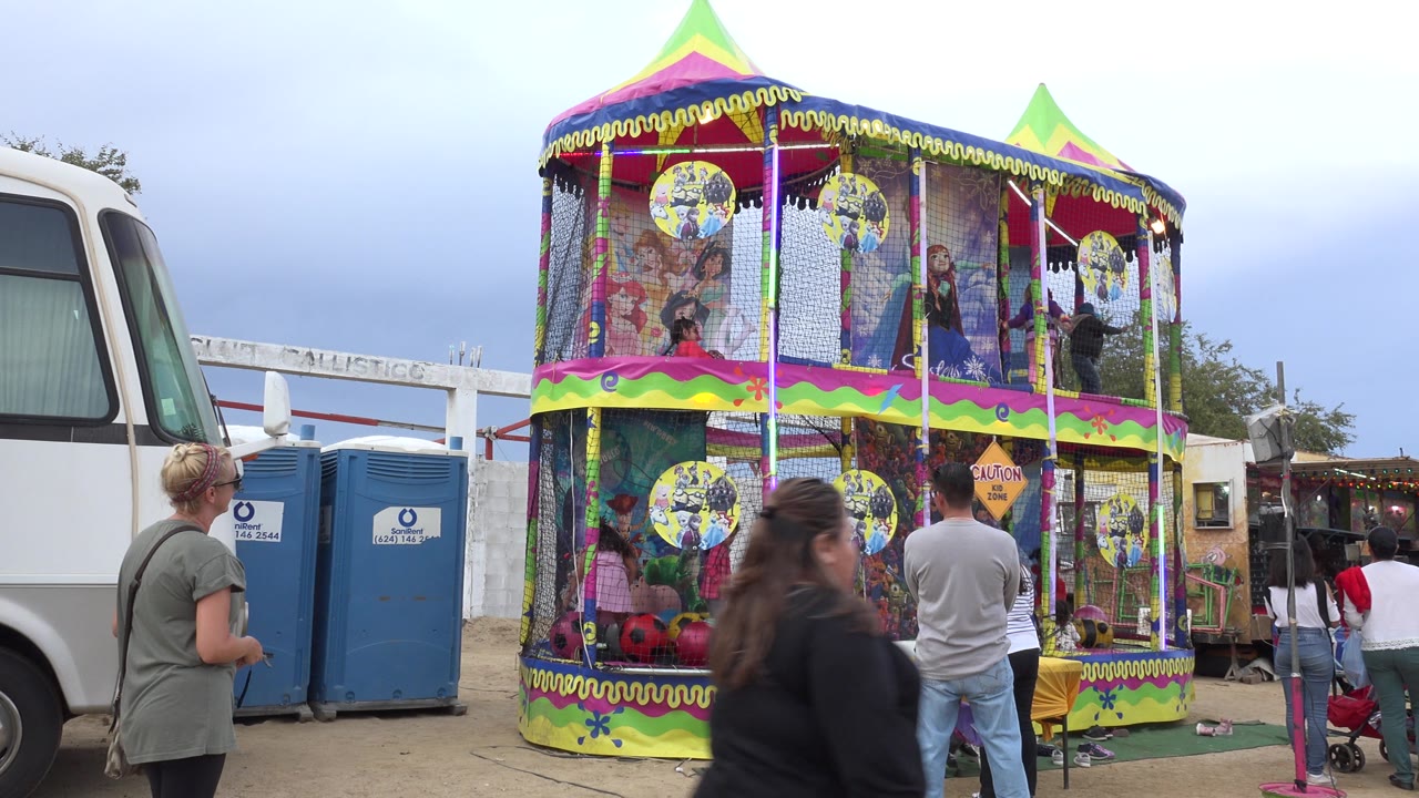 Colorful double-decker bounce house with children inside and adults nearby.
