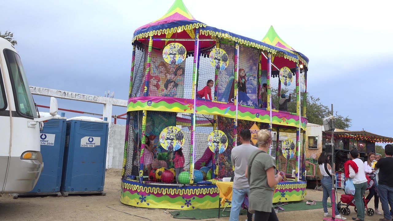 Colorful bouncy castle with children inside and adults standing nearby at a fair.