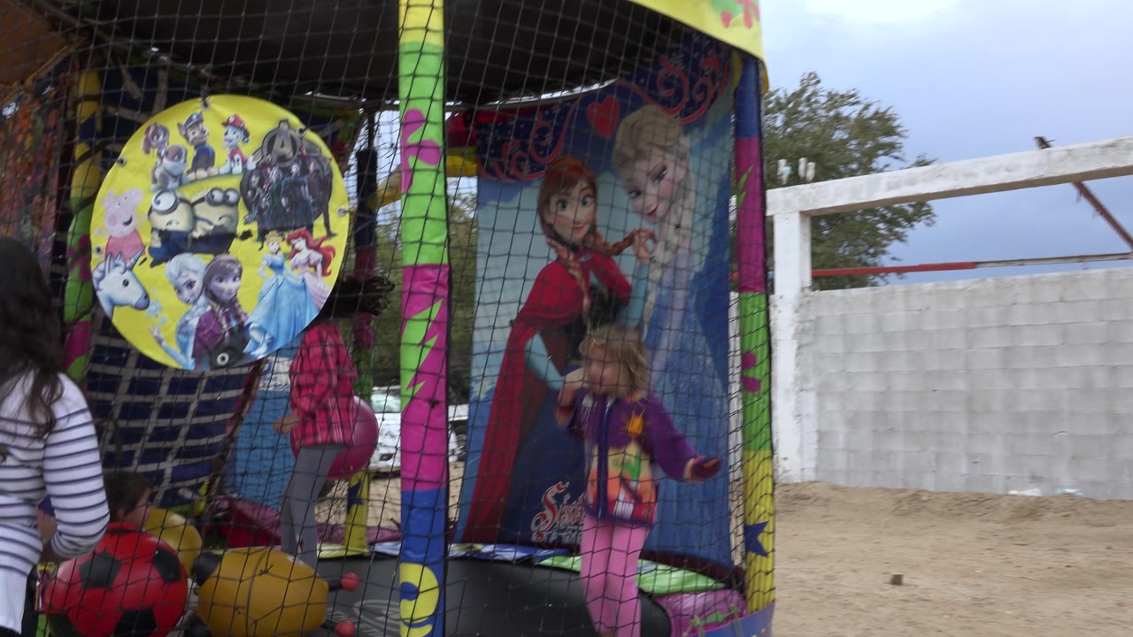 A child in pink jumps near a side panel with cartoon princess artwork as an adult stands outside the netted trampoline in San Jose del Cabo, Mexico.