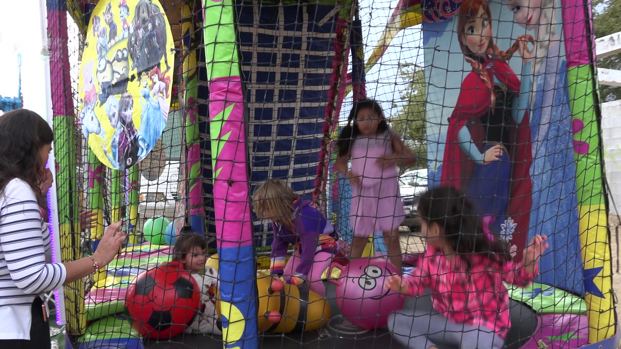 Children shift positions inside the inflatable ball pit as an adult watches through the net.