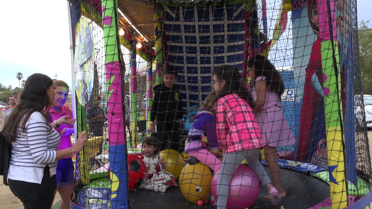 Children and adults around a netted trampoline with colorful balls