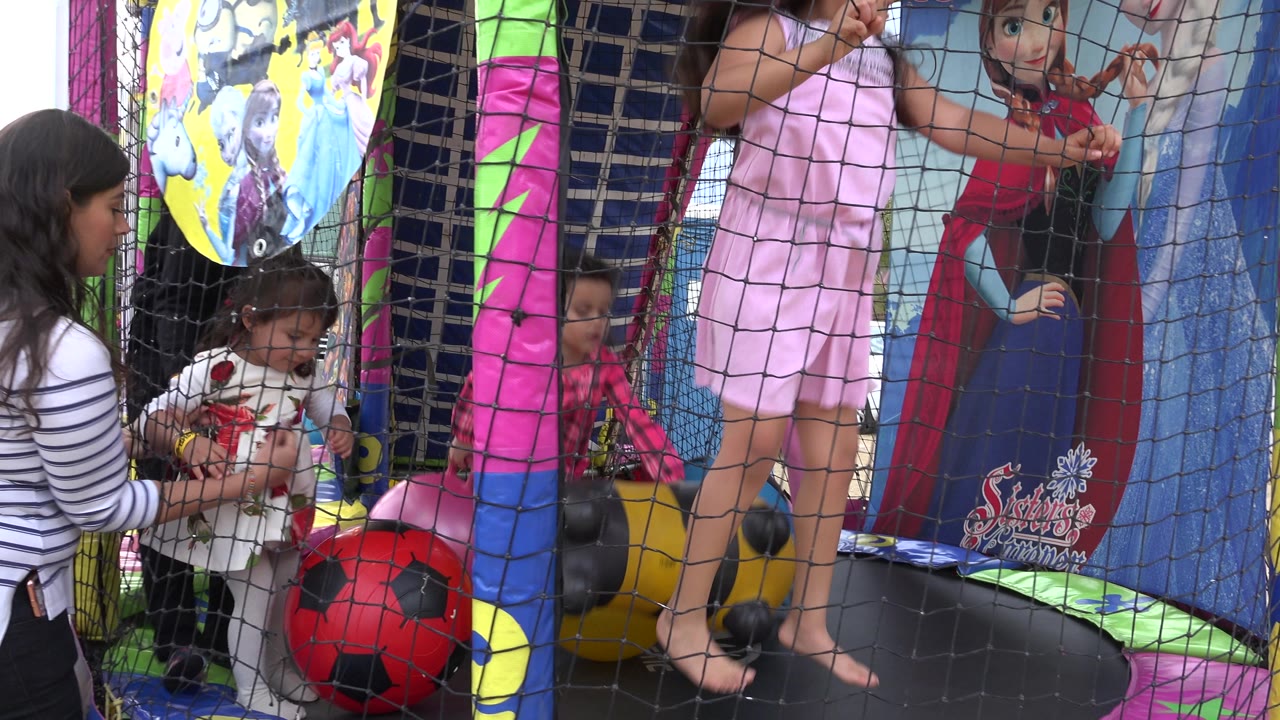 Adult or older girl helps a small child near the entrance of the inflatable.