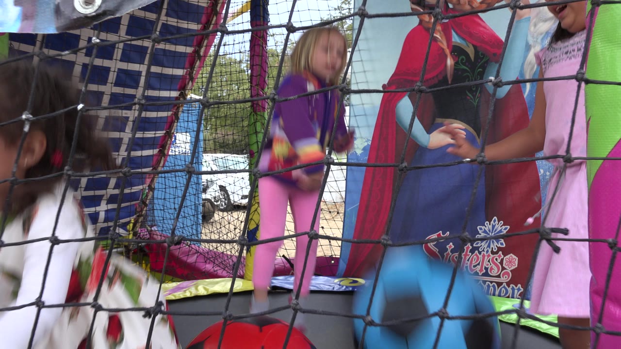 At 0:01 in San Jose del Cabo, Mexico, a small child is mid-jump near the center as other children and adults appear partly cropped behind the foreground net.