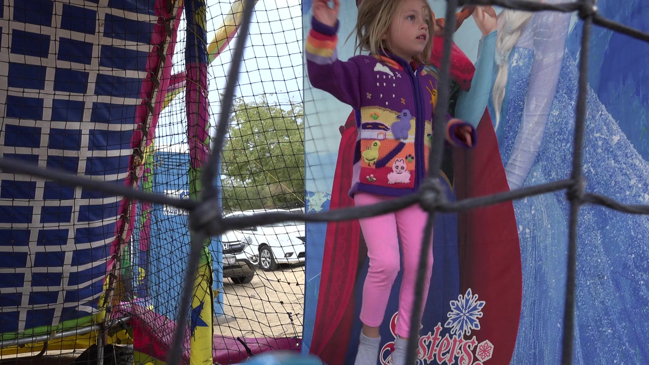 Child standing inside a netted trampoline beside cartoon panels.