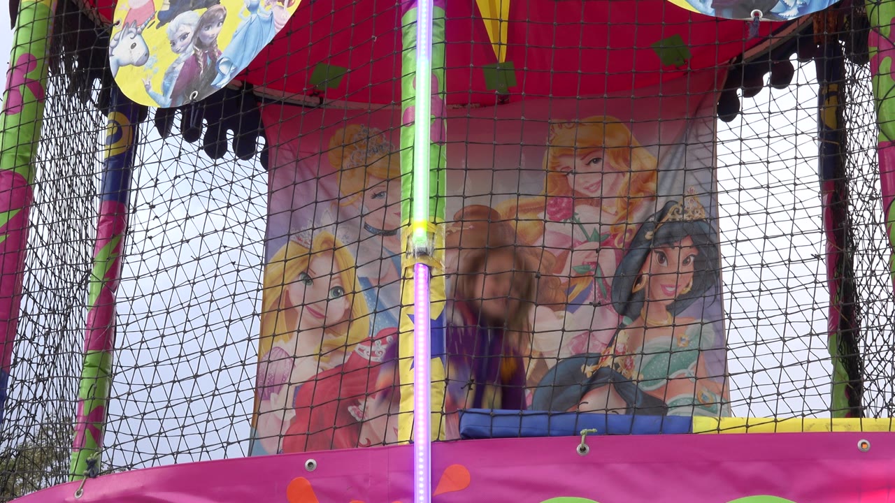 Blond girl bouncing behind netting with princess artwork behind her.