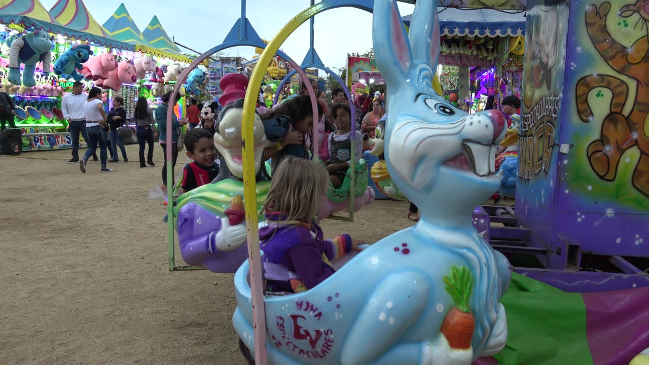 Girl in purple jacket seated on a blue bunny fair ride