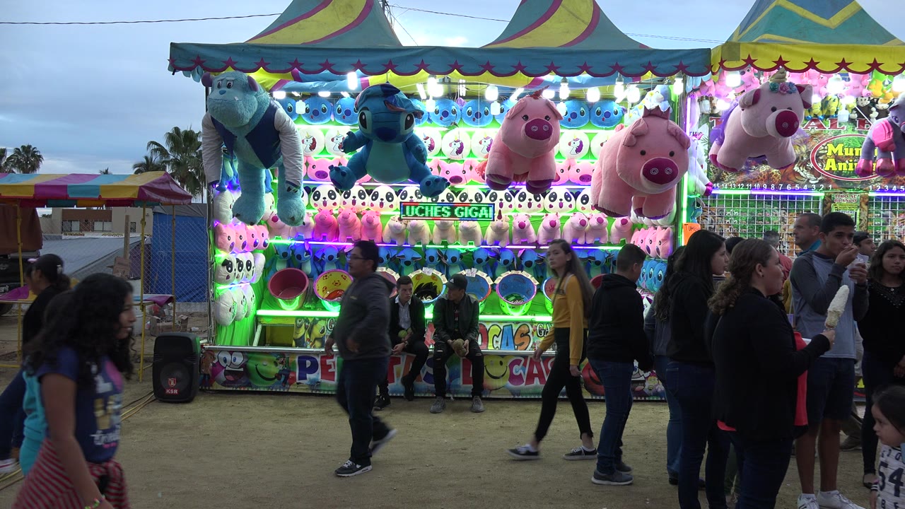 Crowd in front of a brightly lit carnival prize booth.