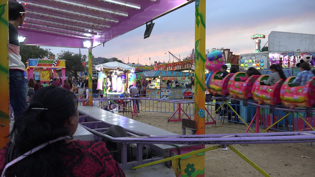 Colorful children's ride seen from behind purple railings at a fairground.