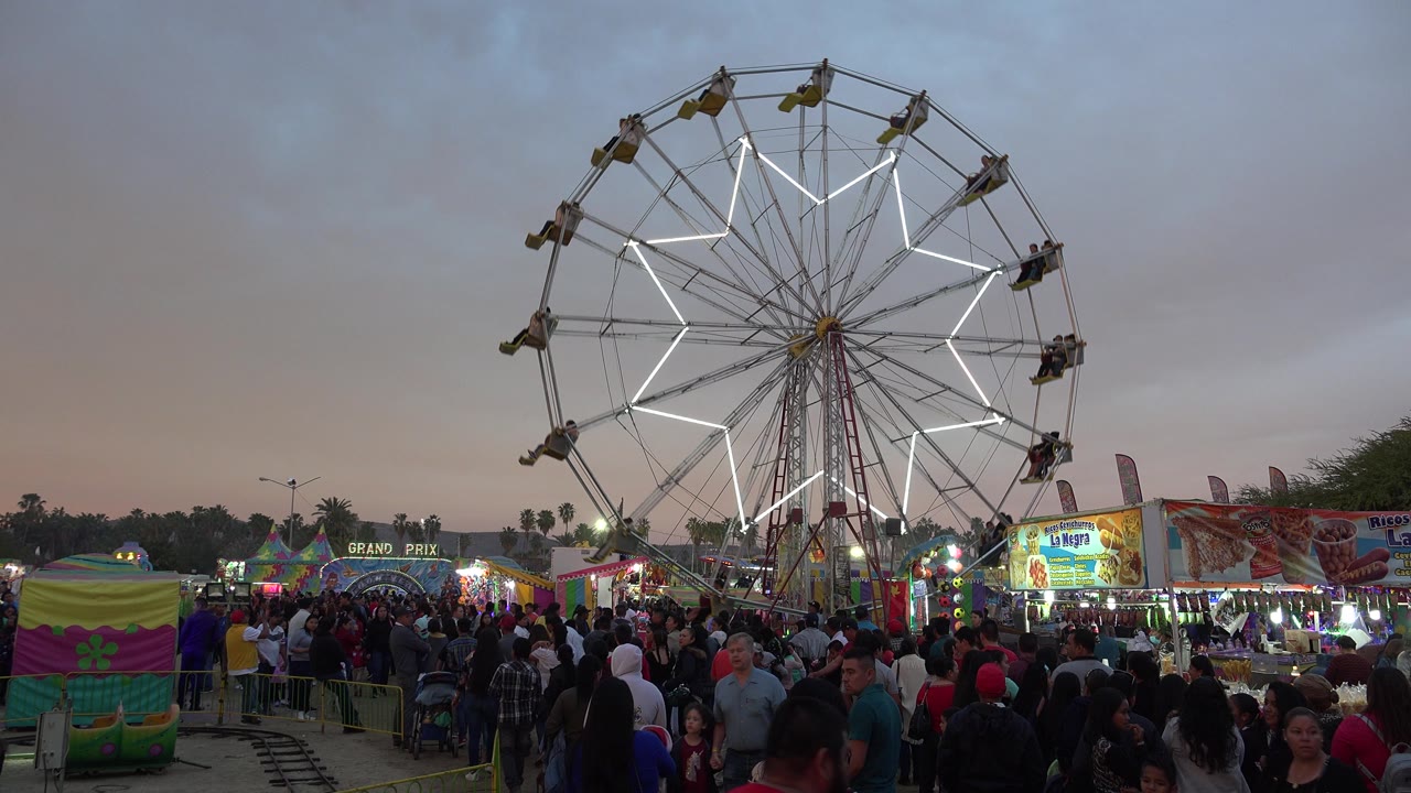 Ferris wheel above a crowded carnival at dusk