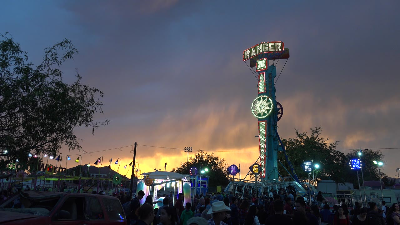 Fairground crowd below a tall Ranger ride sign at sunset.