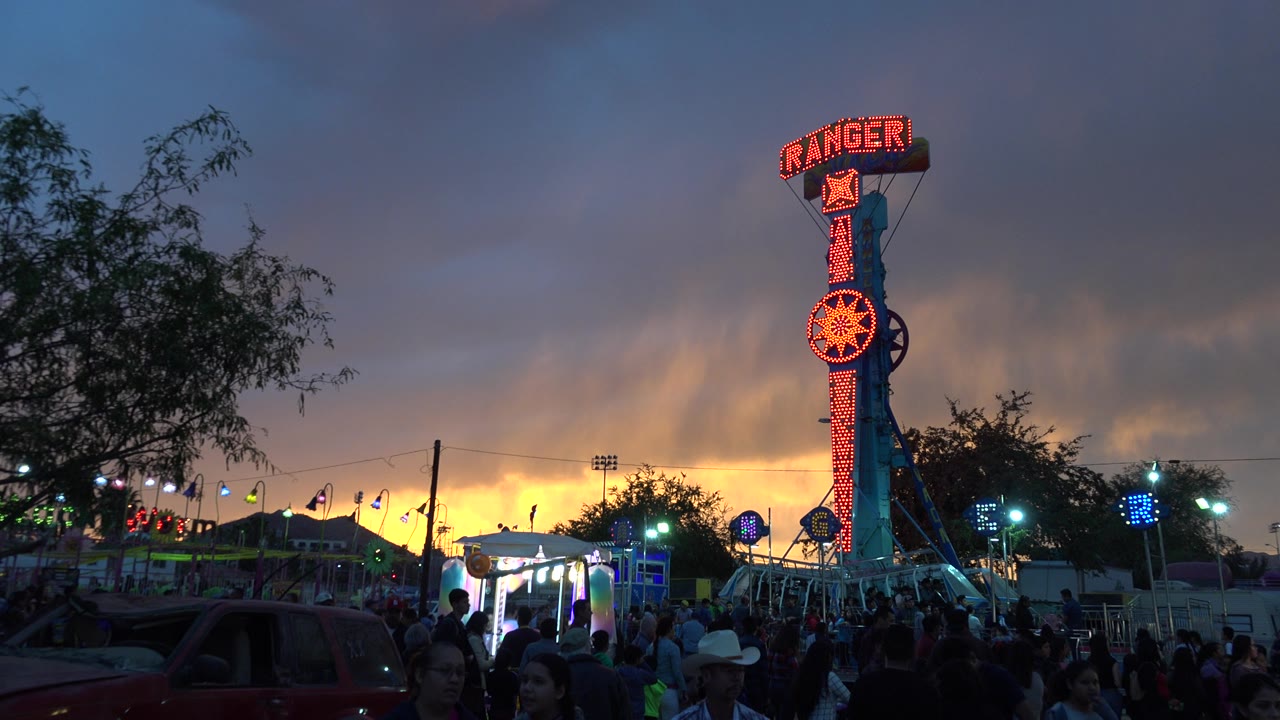Crowded amusement park at sunset with a tall red Ranger ride sign.