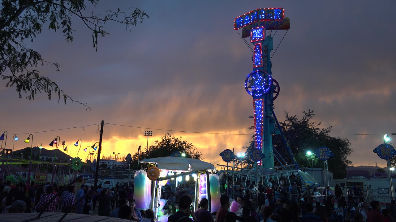 Blue flashing Ranger sign beside fairground lights at dusk.