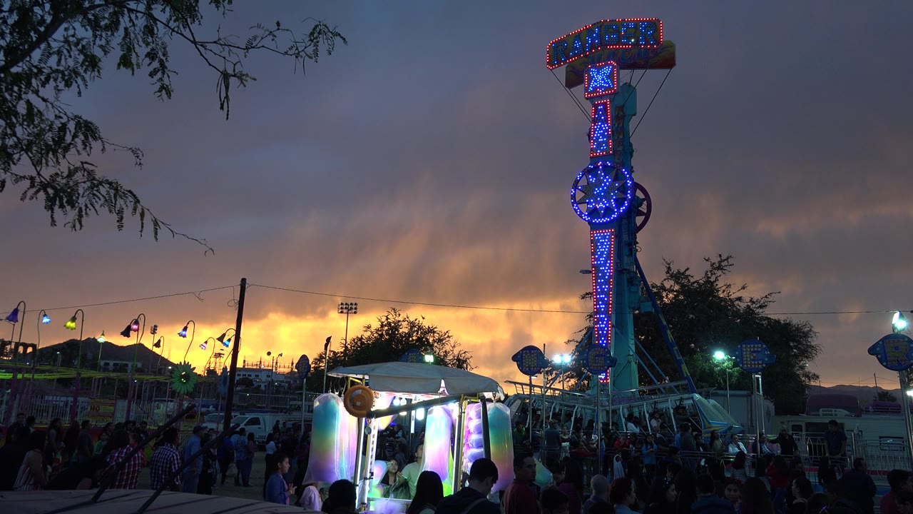 Illuminated Ranger ride above a crowded fairground at dusk.