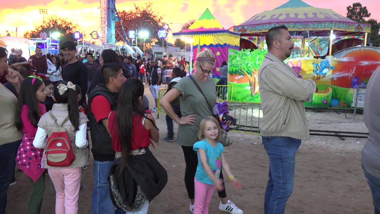 Families and children near a colorful amusement ride at sunset.