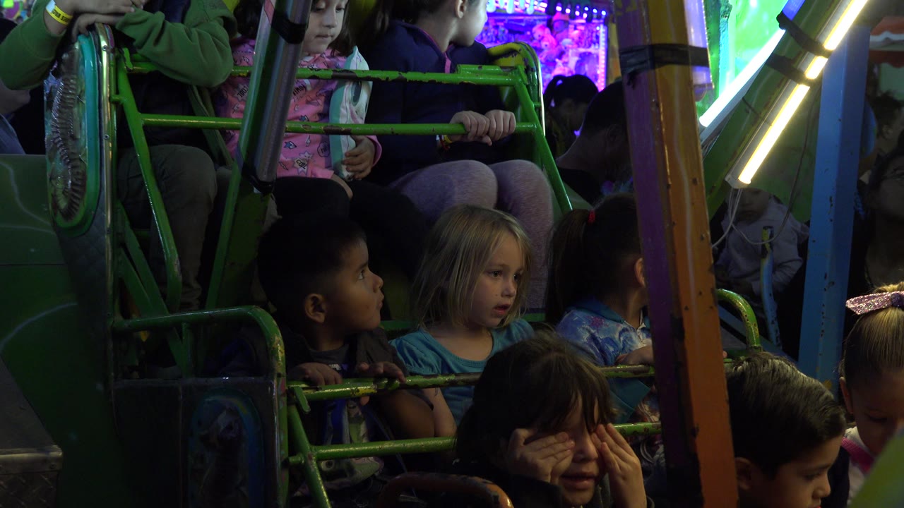 Carnival ride car with children framed by colored supports.