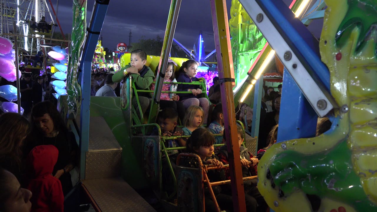 Children and adults on a green amusement ride at night