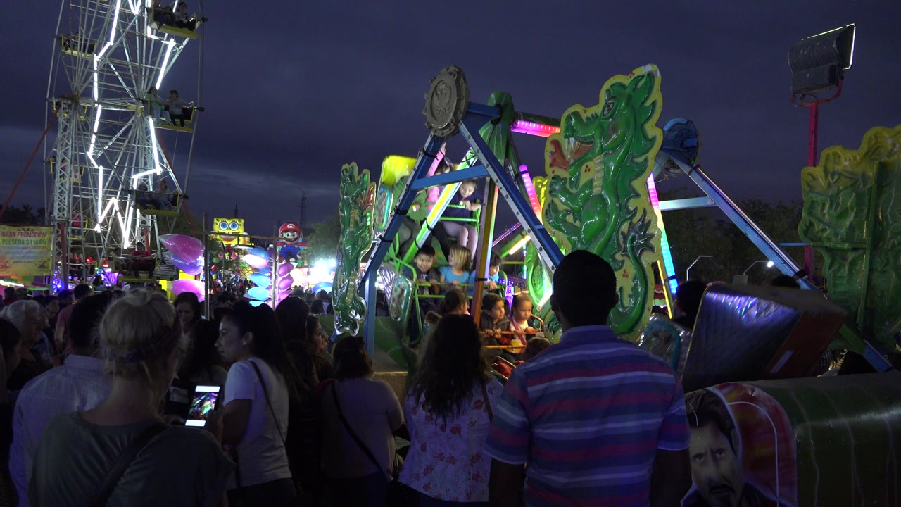 Crowd watching a lit carnival ride at night