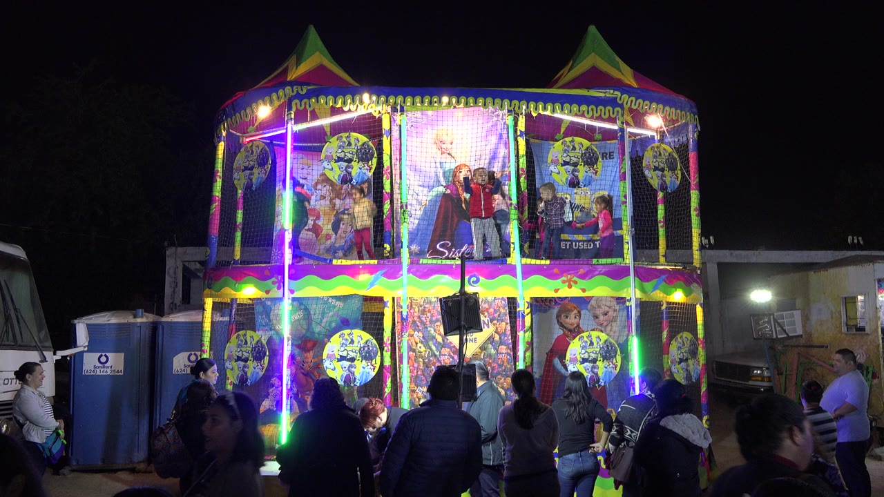 Nighttime children’s theater facade with spectators in front.