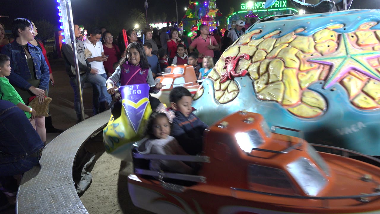 Children ride colorful boat seats on a night merry-go-round.