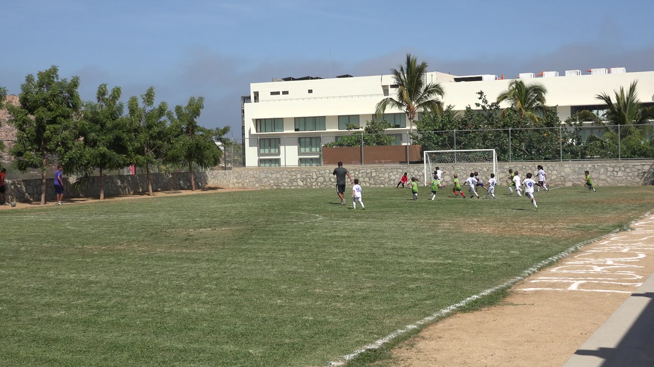 Children run toward the right side of the goal during a football match.