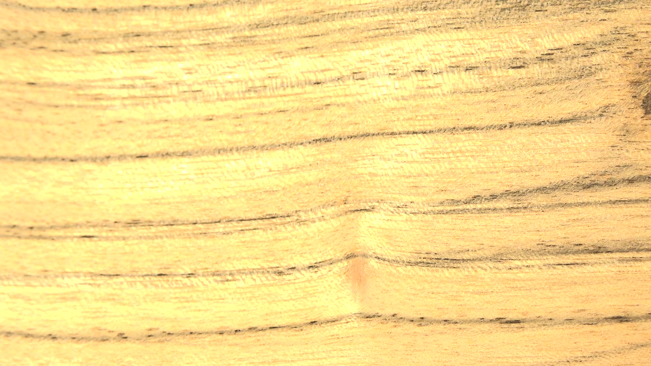 Close-up yellow-orange wood grain fills the opening frame in Westminster, Colorado, with dark horizontal streaks and no visible people.
