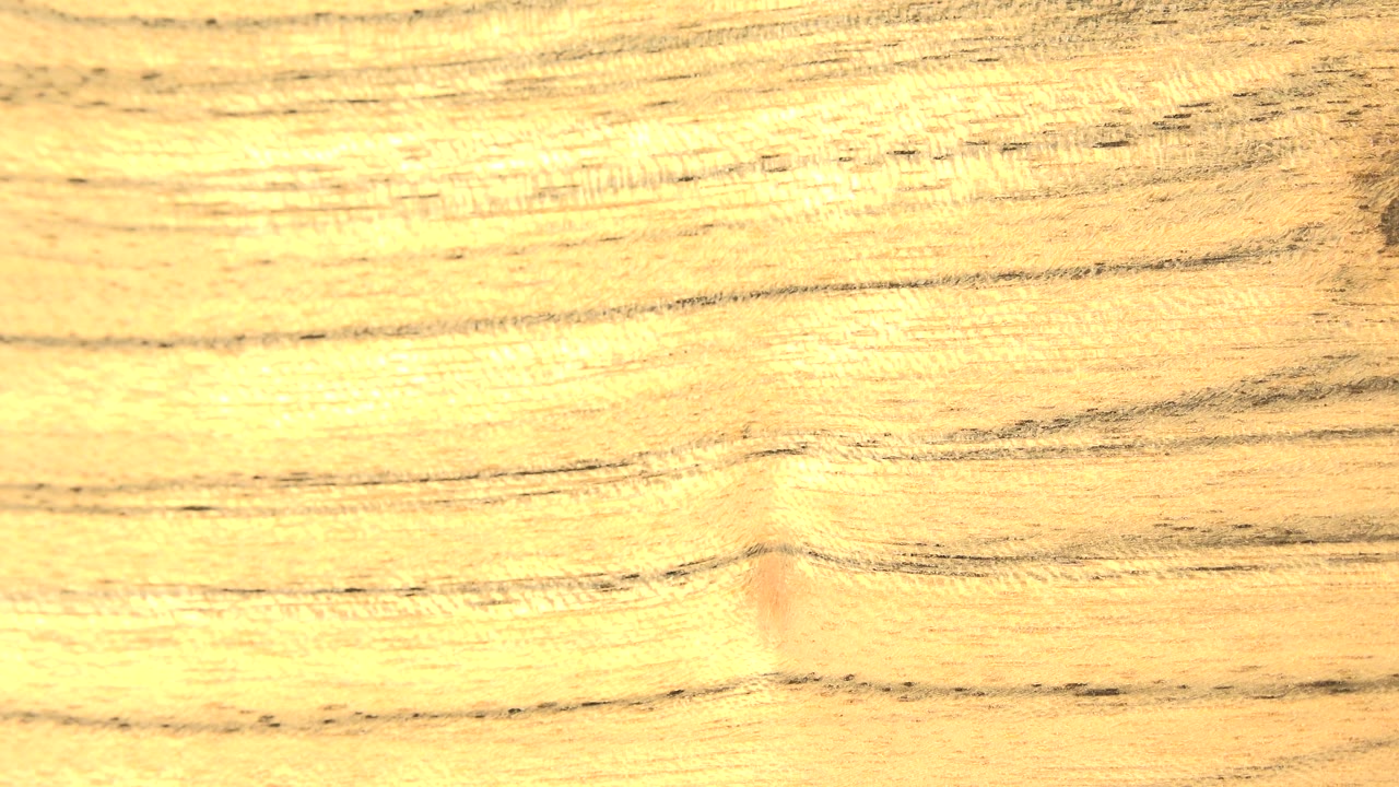 A second close frame shows the yellow-orange wood surface shifted across the view, with darker grain bands and no visible people.