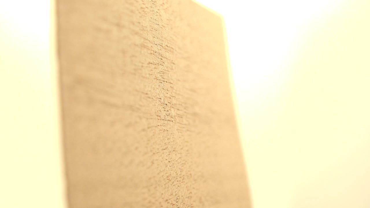 Vertical edge of a tan wood board in bright light.