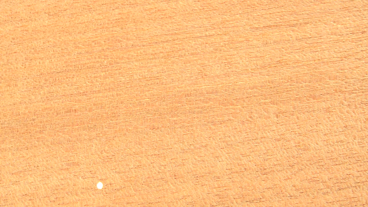 Light tan wood texture with a small bright spot near the lower center.