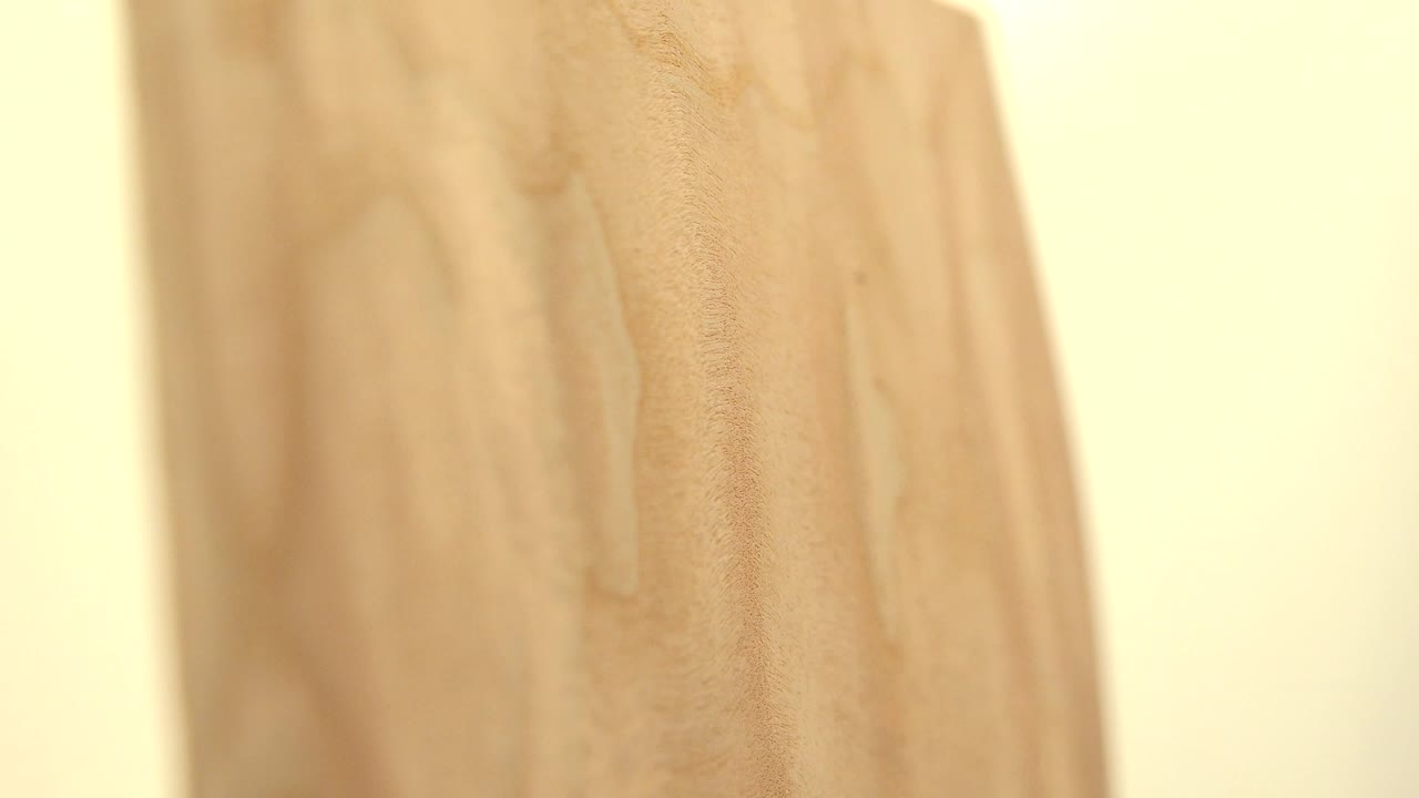 Soft side close-up of a pale yellow wood board in Westminster, Colorado, with vertical grain and a bright cream background, no visible people.