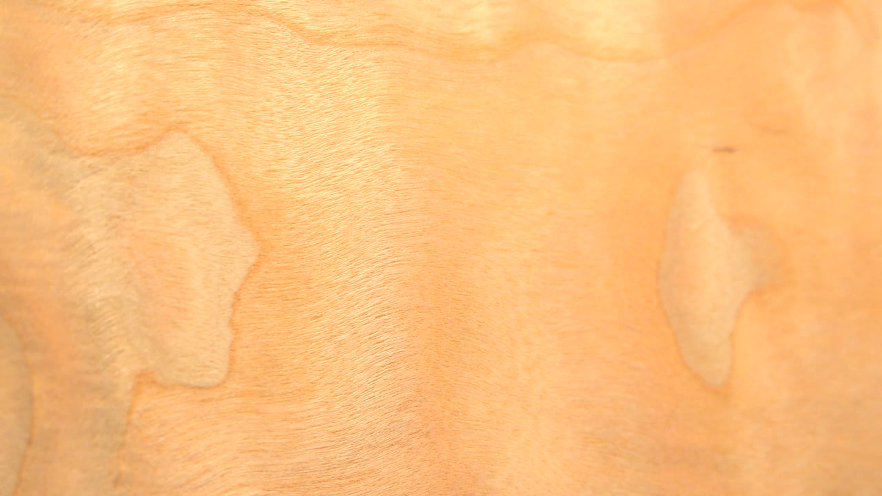 Flat close-up of a yellow wood surface with knots and grain patterns.