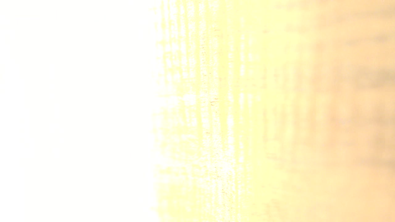 Overexposed close-up of a warm wood-like surface in Westminster, Colorado, with faint vertical grain markings and no visible people.