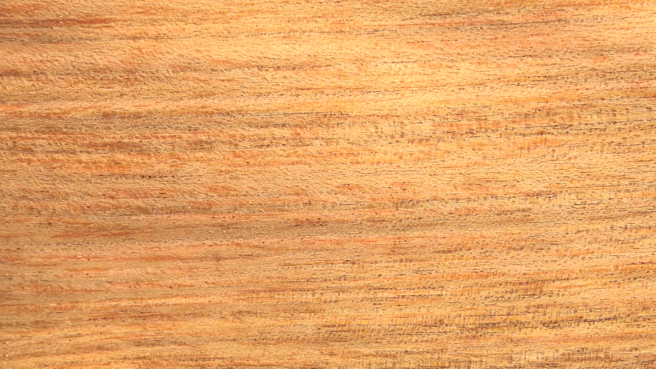 The brown board surface remains close to full frame, showing darker streaks and fine texture detail, with no visible people.