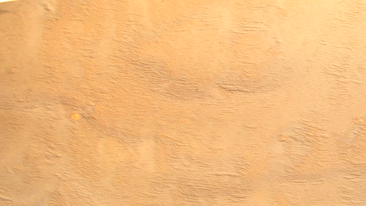 The yellow wood board has rotated so a pale edge and white overexposed background appear along the top, with no visible people.