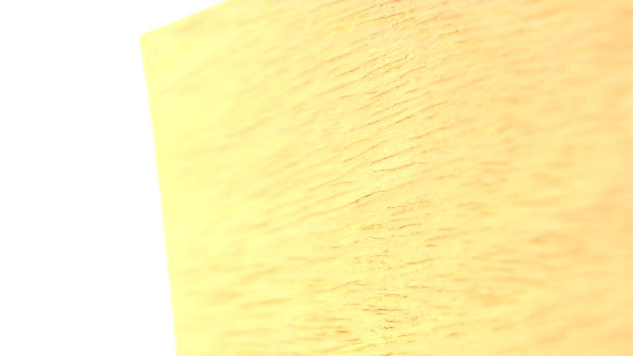 At 0:01, the yellow textured object sits at a slightly different angle with grain visible across the lit surface and no visible people.