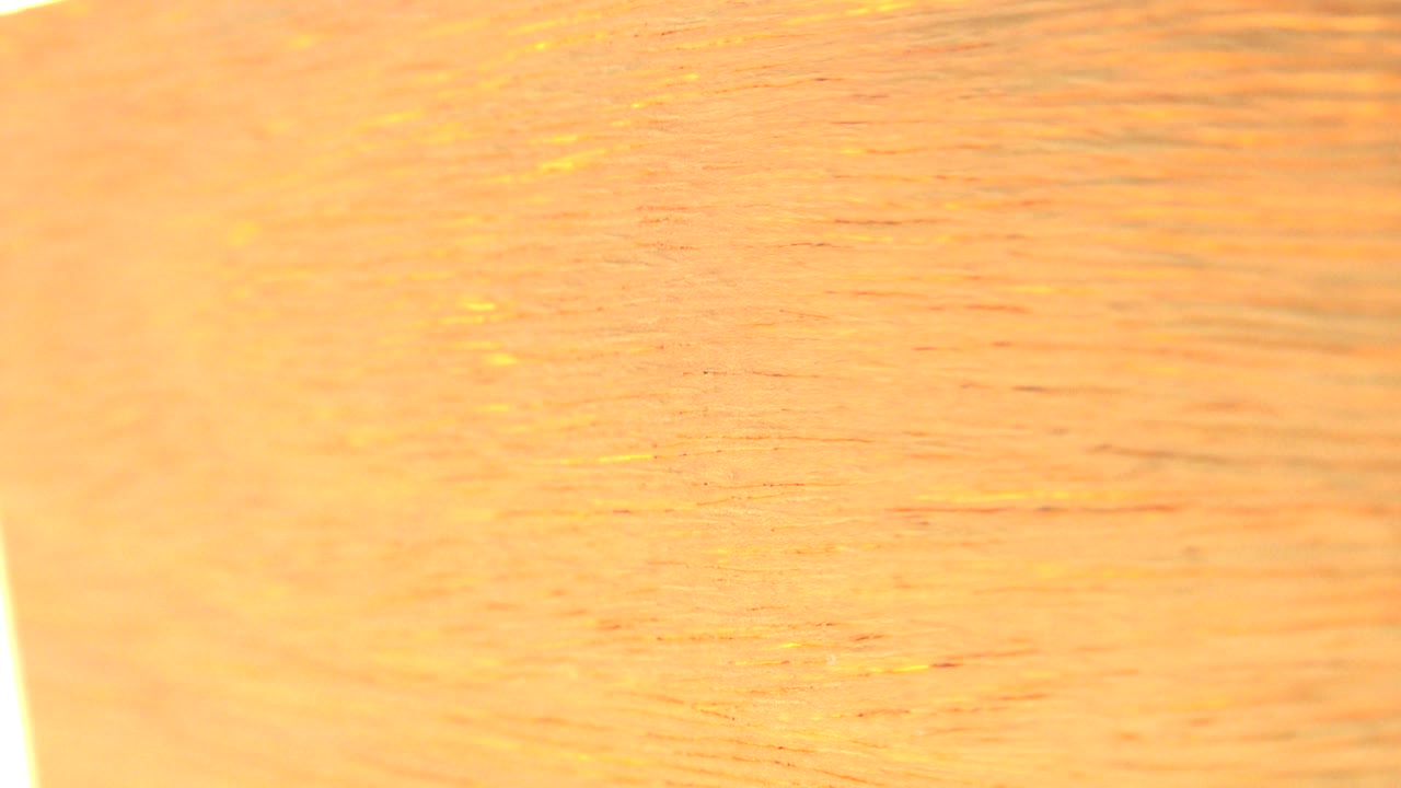 Close-up of warm gold textured paper with bright edge light.
