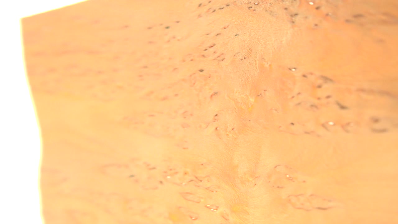 At 0:01, the yellow object remains close to the lens with fine specks across the surface and a bright vertical white band on the left, with no visible people.