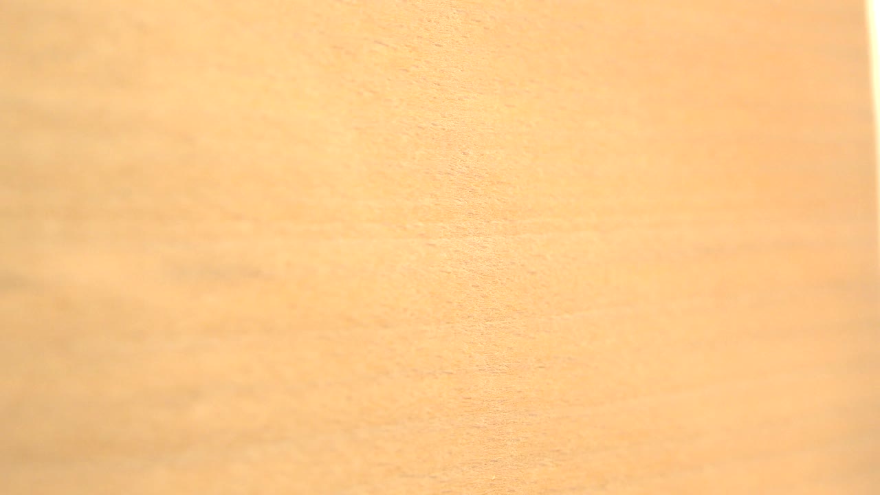 The Westminster, Colorado clip shows the wood-patterned sheet slightly shifted, with honey-toned grain and a narrow bright vertical strip near the left side, no visible people.