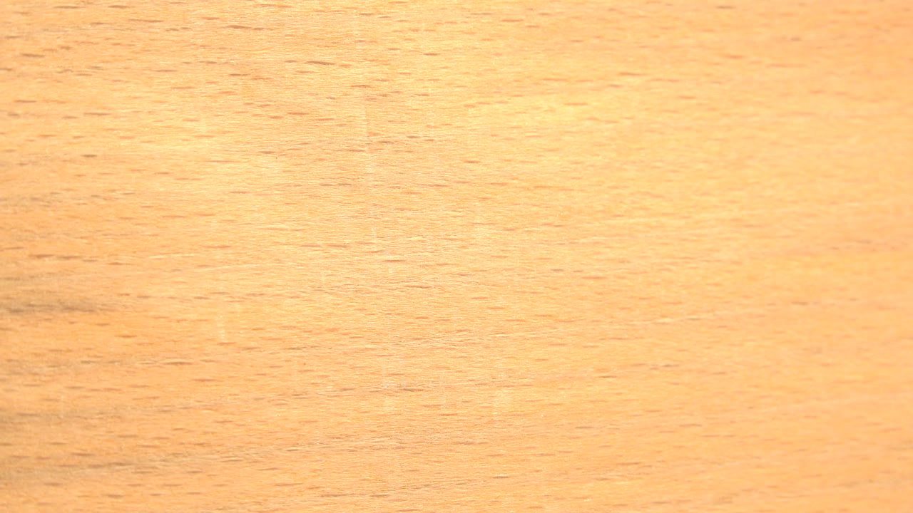 Wood grain surface filling the frame in warm orange light.
