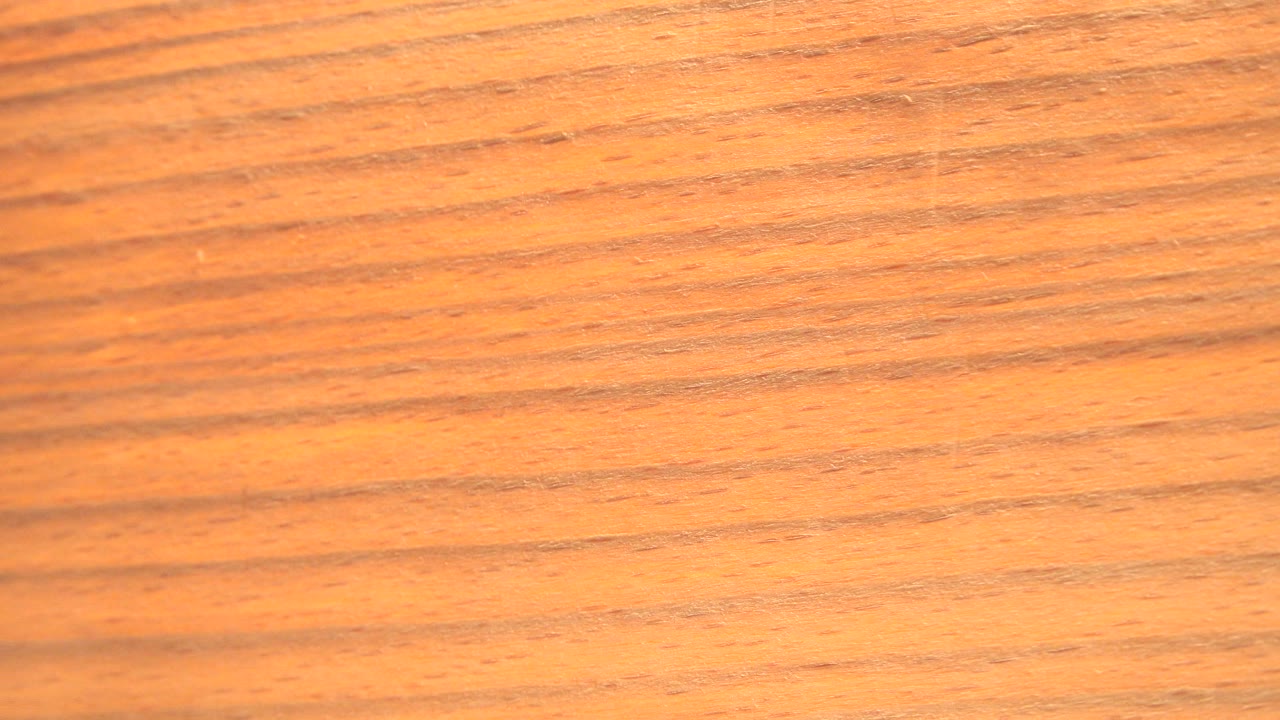 A close yellow-orange textured surface fills the frame in Westminster, Colorado 2015 footage, with darker grain lines and no visible people.