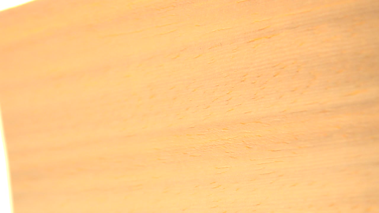 A tight Westminster, Colorado frame of tan wood grain with warm amber streaks and a bright white flare along the left edge, no visible people.
