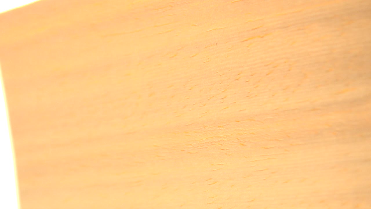 The Westminster, Colorado clip holds on a warm tan wooden surface while a narrow vertical white light streak appears near the right side, no visible people.