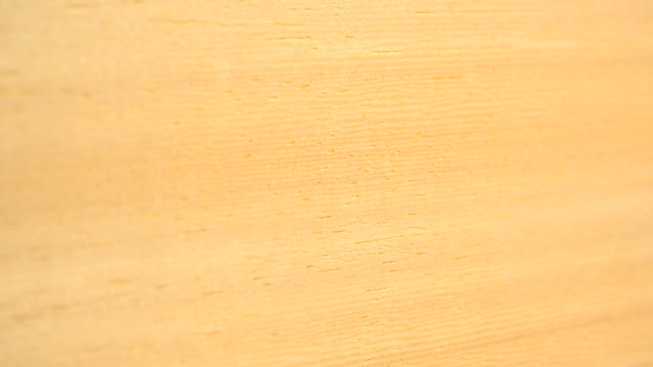 Warm yellow close-up surface texture from the Westminster, Colorado 2015 clip, with faint grain lines, small marks, soft focus, and no visible people.