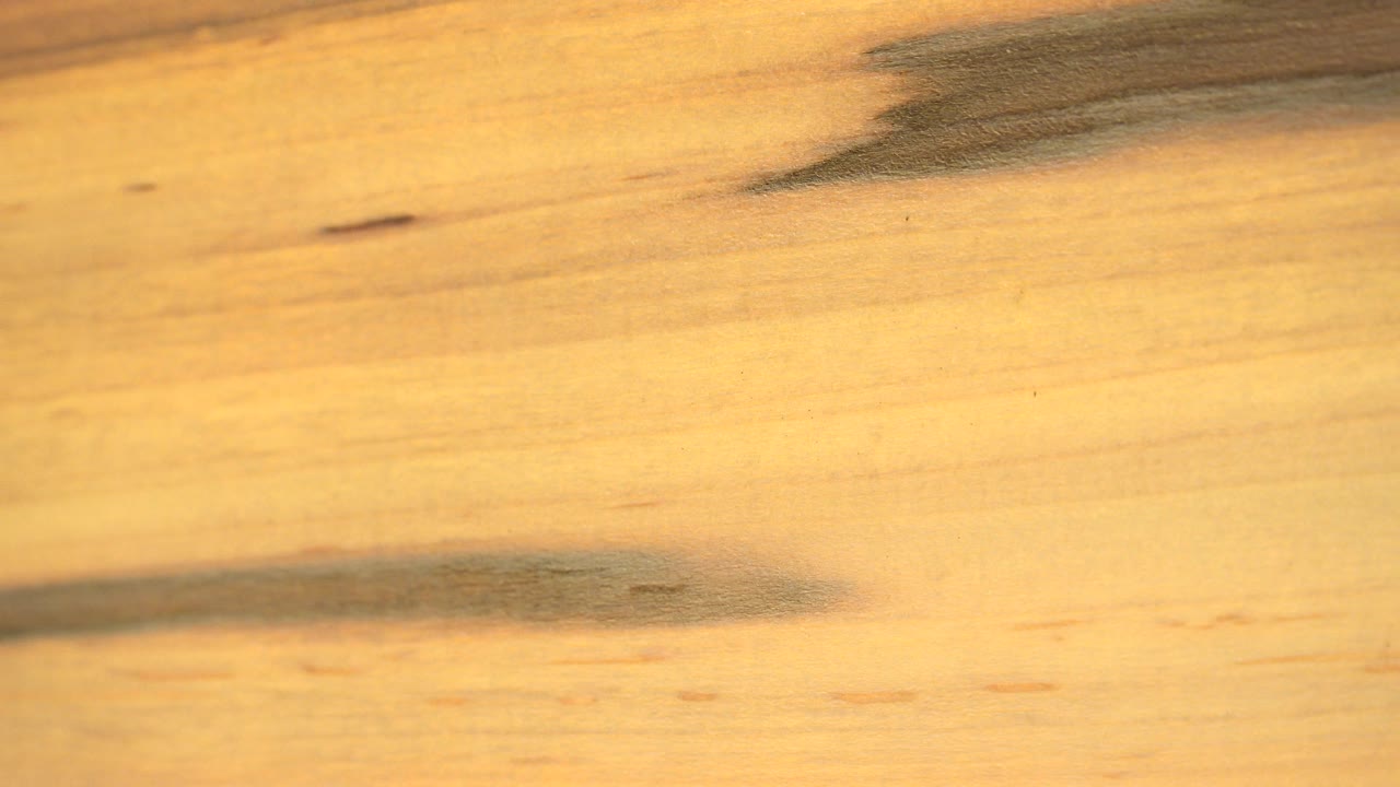 The second Westminster, Colorado frame keeps the pale wood in close view as dark grain bands sit near the upper right and lower center, with no visible people.