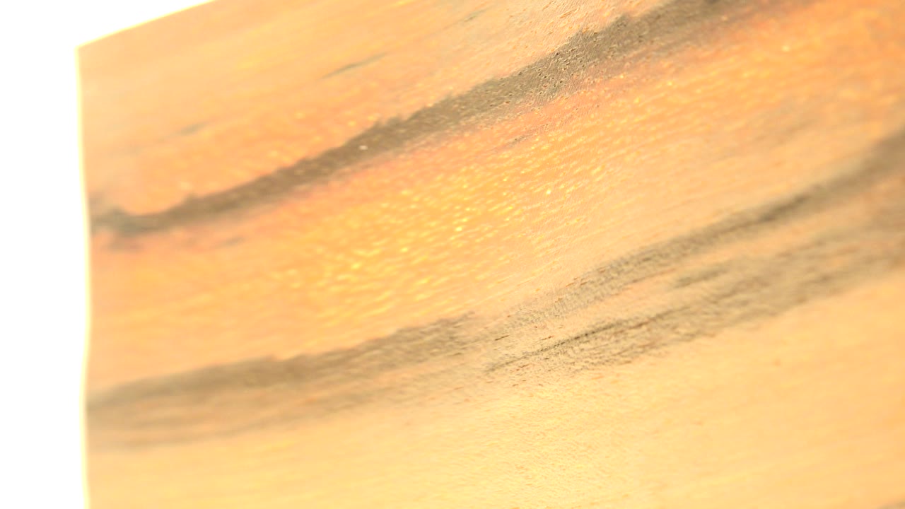 A second close frame holds on the orange painted surface in Westminster, Colorado, with the dark brushlike band shifted slightly across the top area and no visible people.