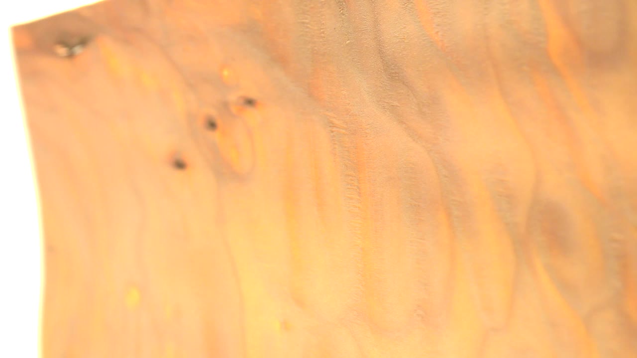 A close Westminster, Colorado frame shows a gold-toned coin surface filling the view, with orange reflections, small dark specks near the top, and no visible people.