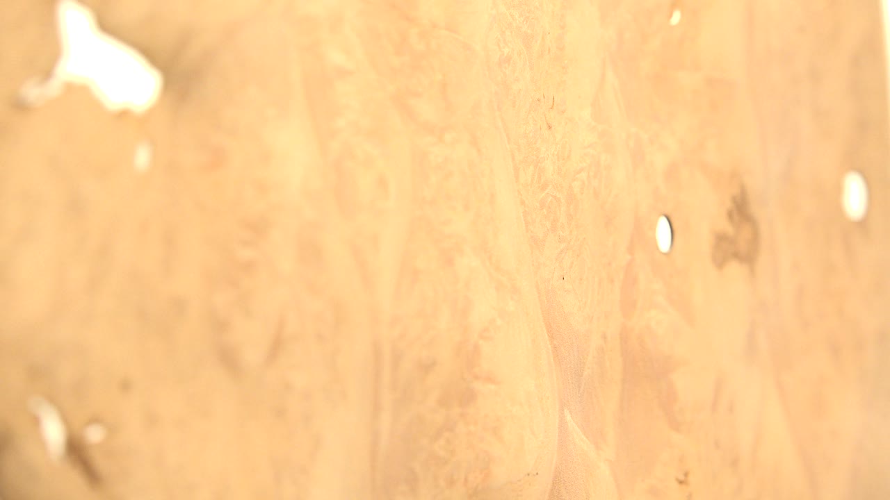 At 0:01, the orange generated surface remains close in frame, with a small white circular point near the right side, blurred texture, and no visible people.